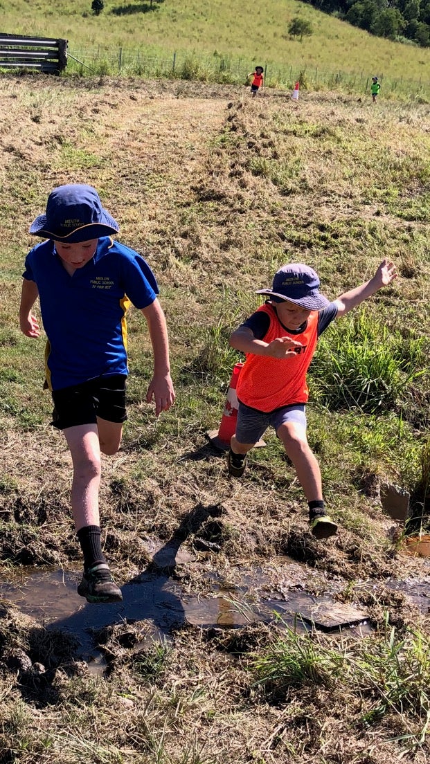 Photo of two students running in a paddock