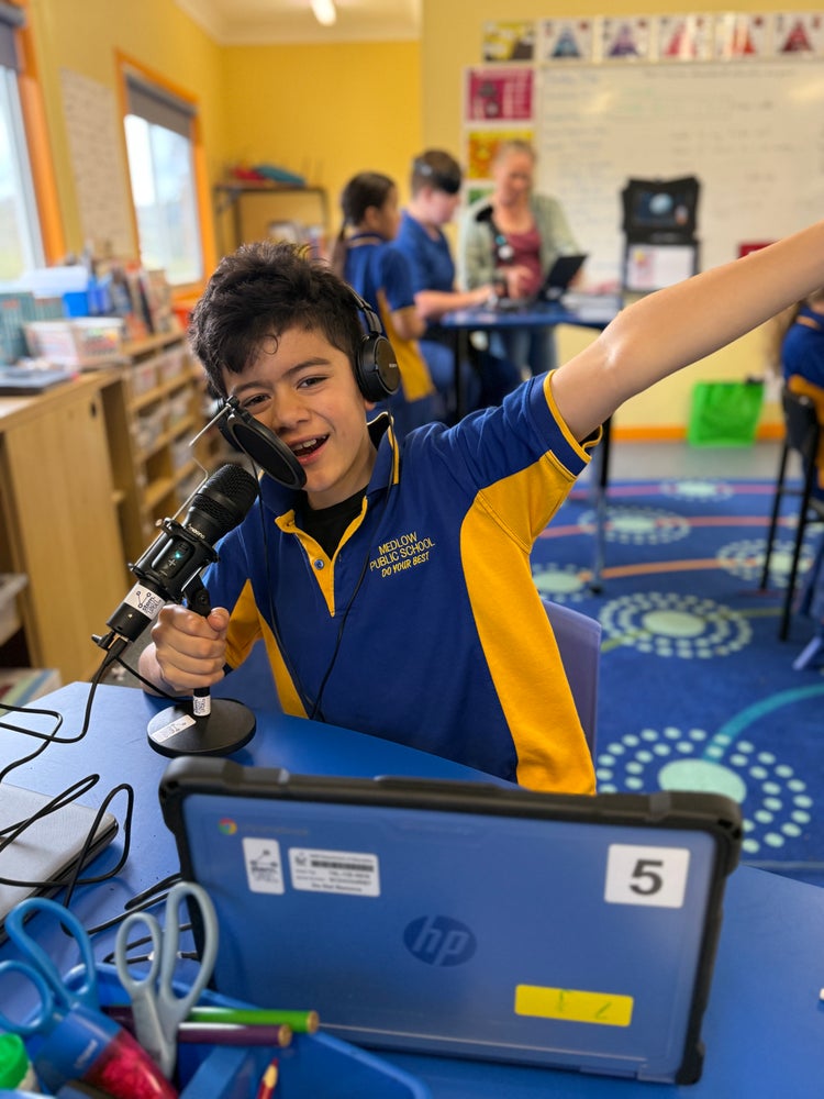 Photo of a student sitting at a table and talking into a microphone