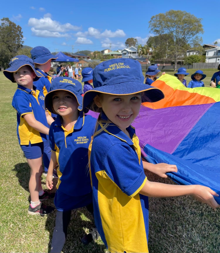 Photo of a group of students holding up a large piece of canvas
